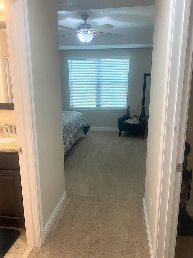 bedroom featuring light colored carpet, a sink, baseboards, and ceiling fan