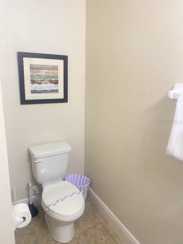 half bathroom with toilet, tile patterned flooring, and baseboards