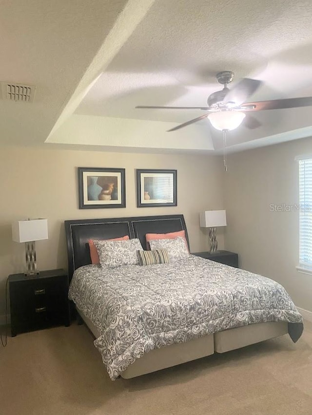 carpeted bedroom with visible vents, ceiling fan, and a textured ceiling