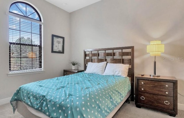 bedroom featuring light carpet and baseboards