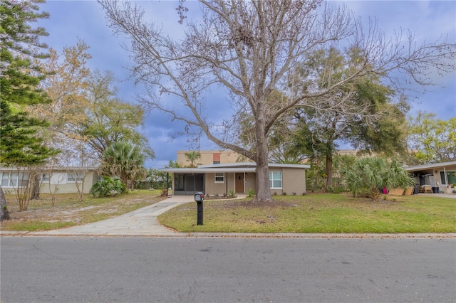 ranch-style house featuring driveway, stucco siding, a carport, and a front yard