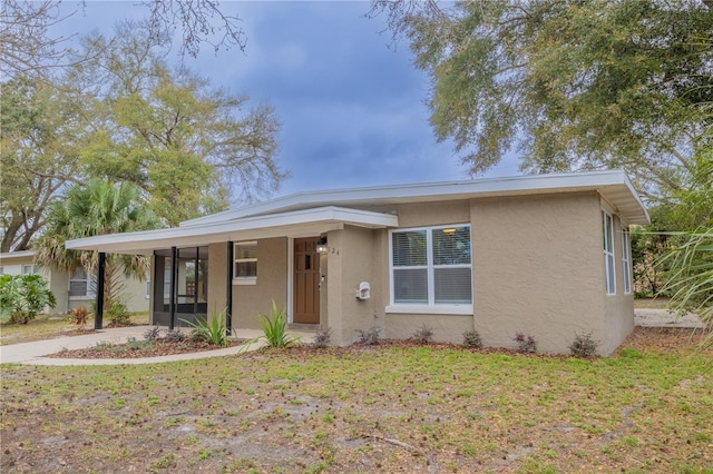 view of front of property featuring driveway, a front yard, and stucco siding