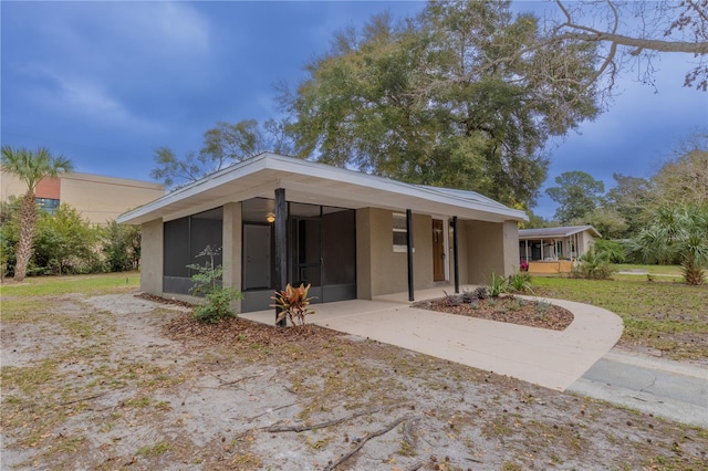 view of front of house with driveway, a sunroom, and stucco siding