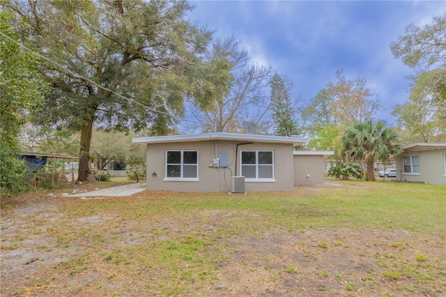 rear view of property featuring a yard, cooling unit, and stucco siding