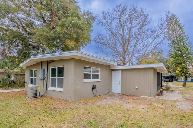 exterior space with a front yard, stucco siding, and central air condition unit