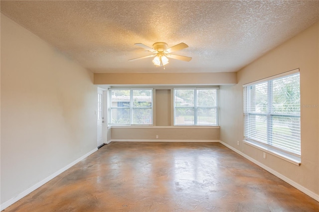 spare room featuring concrete flooring, a textured ceiling, baseboards, and a ceiling fan