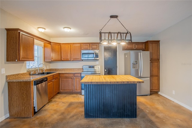 kitchen with a kitchen island, a sink, hanging light fixtures, wooden counters, and appliances with stainless steel finishes