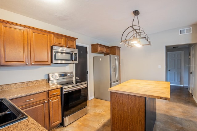 kitchen featuring finished concrete flooring, wood counters, appliances with stainless steel finishes, and brown cabinetry