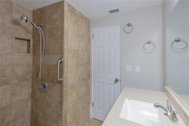 full bathroom featuring visible vents, a tile shower, and vanity