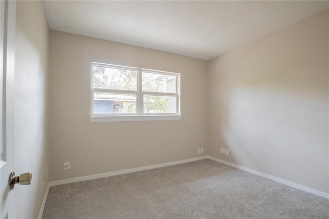 unfurnished room with light carpet and baseboards