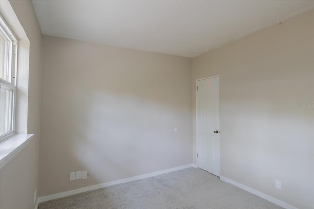 empty room featuring baseboards and light colored carpet