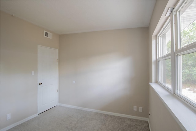 spare room with visible vents, a healthy amount of sunlight, light carpet, and baseboards