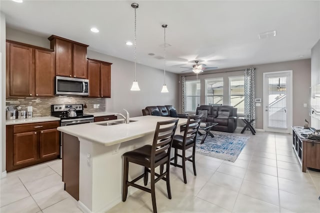 kitchen with sink, tasteful backsplash, a kitchen breakfast bar, stainless steel appliances, and a kitchen island with sink