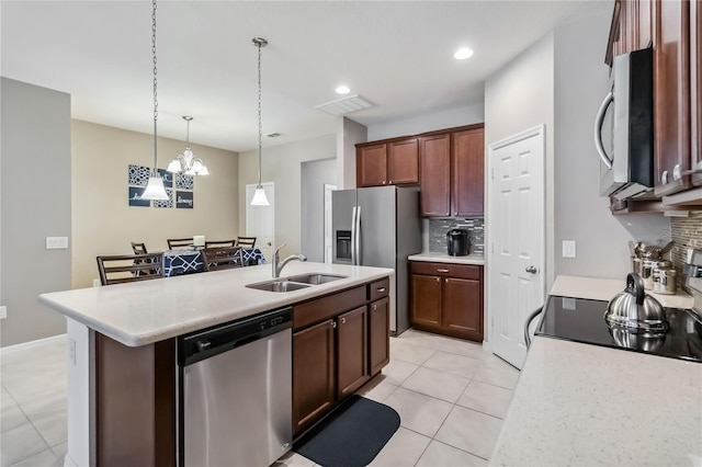 kitchen with pendant lighting, sink, stainless steel appliances, an island with sink, and decorative backsplash