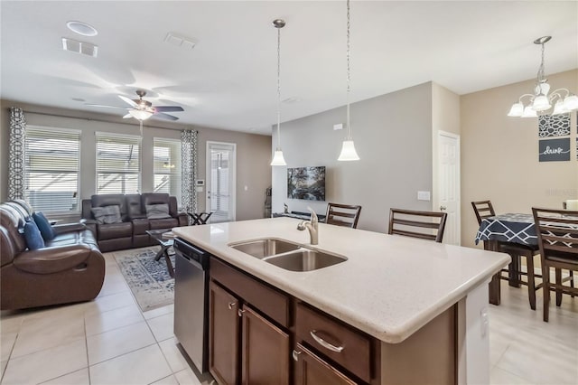 kitchen with pendant lighting, sink, light tile patterned floors, dishwasher, and a kitchen island with sink