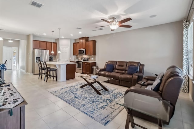 living room featuring sink, light tile patterned floors, and ceiling fan