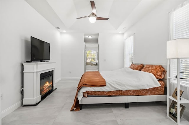 bedroom featuring ceiling fan, ensuite bathroom, and a raised ceiling