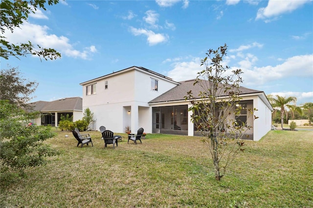 back of property featuring an outdoor fire pit, a sunroom, and a lawn