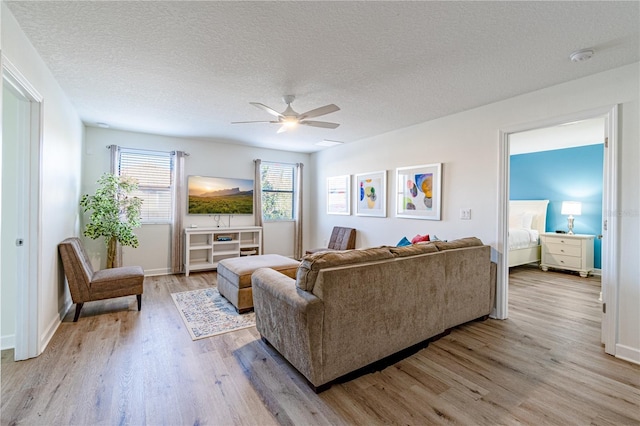 living room with ceiling fan, a textured ceiling, and light hardwood / wood-style floors