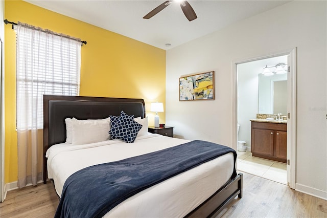 bedroom with ceiling fan, ensuite bathroom, sink, and light hardwood / wood-style flooring