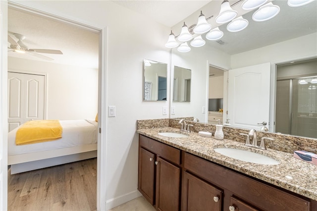 bathroom with hardwood / wood-style flooring, ceiling fan, vanity, an enclosed shower, and a textured ceiling