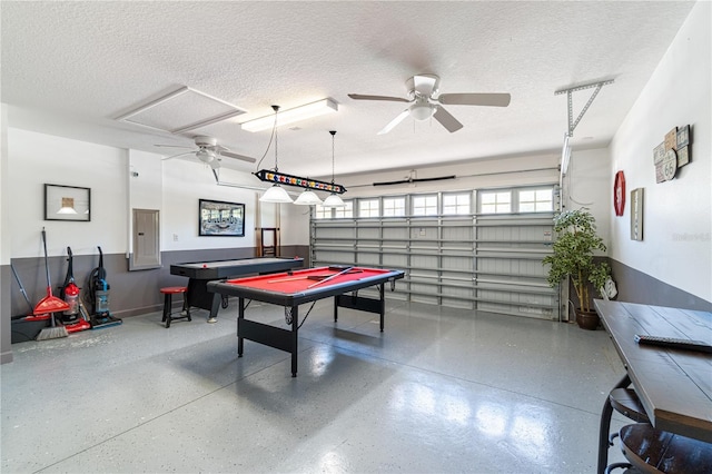 recreation room with ceiling fan, electric panel, and a textured ceiling