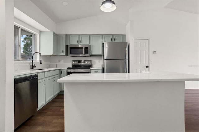 kitchen featuring dark wood-type flooring, lofted ceiling, sink, light stone counters, and appliances with stainless steel finishes