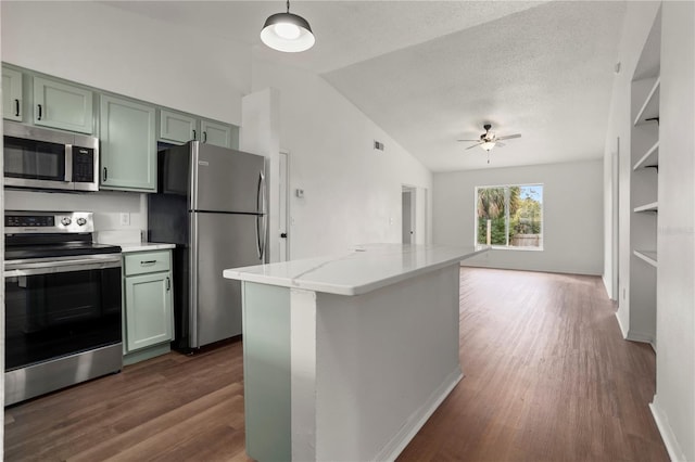 kitchen featuring light stone counters, stainless steel appliances, green cabinetry, and lofted ceiling