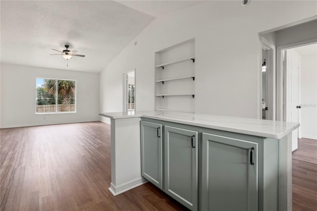 bar featuring dark wood-type flooring, lofted ceiling, a textured ceiling, ceiling fan, and light stone countertops