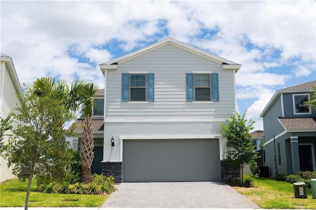 view of front facade featuring cooling unit, a garage, and a front yard