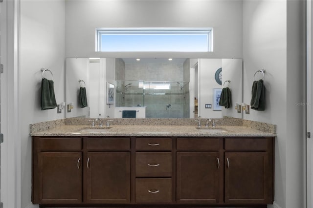 bathroom featuring a shower with door, vanity, and a healthy amount of sunlight