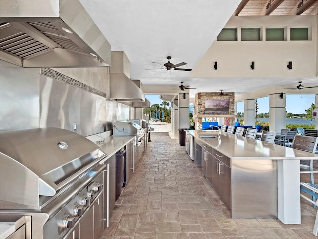 kitchen featuring ceiling fan, island exhaust hood, range hood, and a breakfast bar area