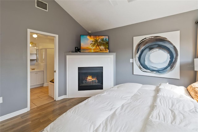 bedroom featuring lofted ceiling, hardwood / wood-style floors, and connected bathroom