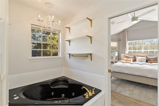 bathroom with wood-type flooring, lofted ceiling, a healthy amount of sunlight, and a bath