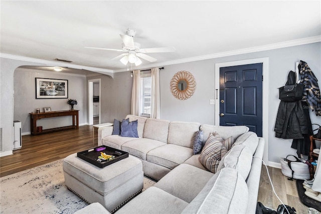 living room featuring dark wood-type flooring, ceiling fan, and crown molding