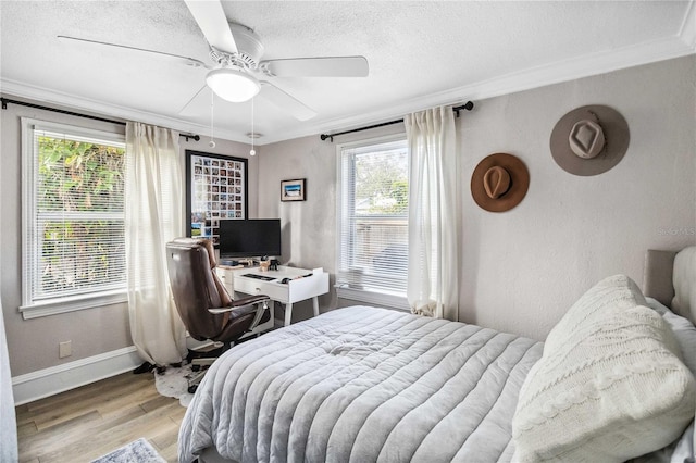 bedroom with ceiling fan, ornamental molding, light hardwood / wood-style floors, and a textured ceiling