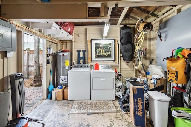 washroom featuring electric water heater, washing machine and clothes dryer, and wood walls