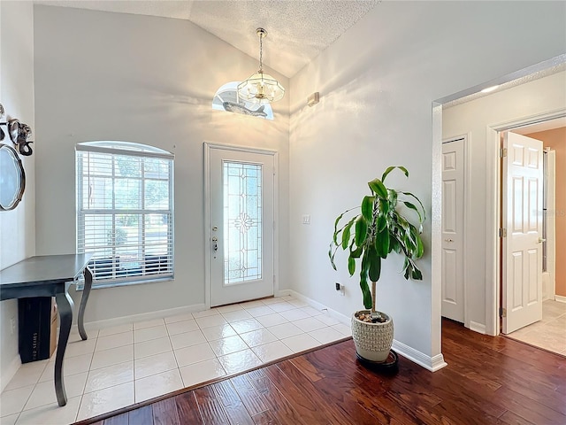 foyer entrance with vaulted ceiling, an inviting chandelier, a textured ceiling, and light hardwood / wood-style floors