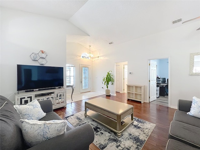 living room featuring dark wood-type flooring, high vaulted ceiling, and a chandelier