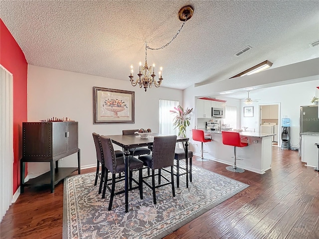 dining space with dark wood-type flooring, vaulted ceiling, washer and dryer, a textured ceiling, and ceiling fan with notable chandelier