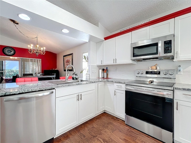 kitchen featuring stainless steel appliances, dark hardwood / wood-style flooring, vaulted ceiling, and white cabinets