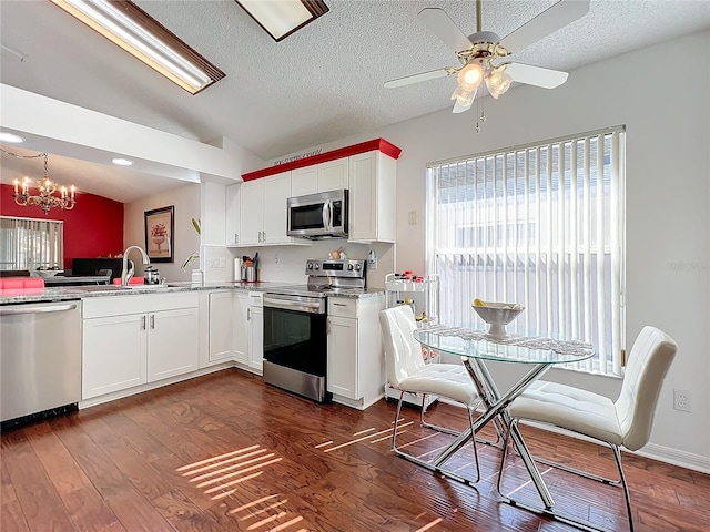 kitchen with sink, appliances with stainless steel finishes, white cabinets, dark hardwood / wood-style flooring, and vaulted ceiling