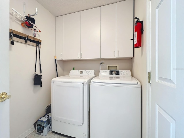 clothes washing area with washer and dryer and cabinets