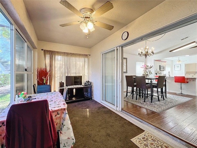 sunroom featuring ceiling fan with notable chandelier