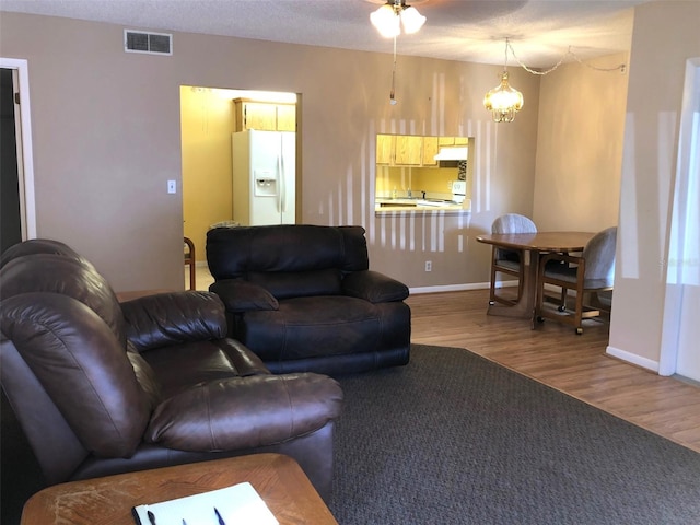 living room featuring hardwood / wood-style flooring, a textured ceiling, and a notable chandelier