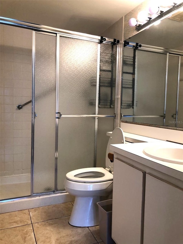 bathroom featuring tile patterned flooring, vanity, toilet, and walk in shower