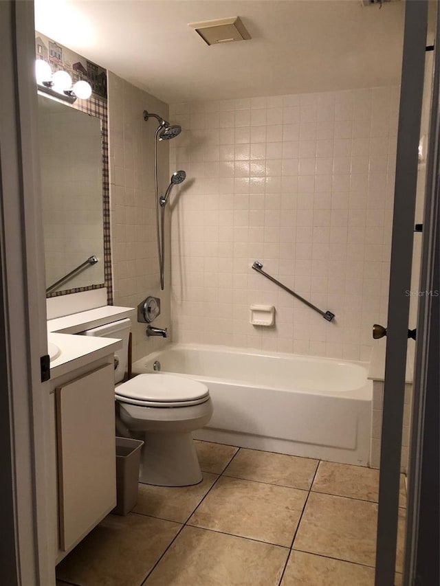 full bathroom featuring tile patterned floors, vanity, toilet, and tiled shower / bath combo