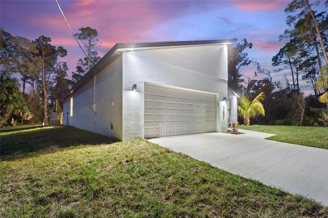 property exterior at dusk with a garage and a yard