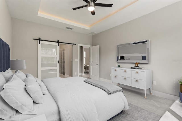 bedroom with a tray ceiling, a barn door, and ceiling fan