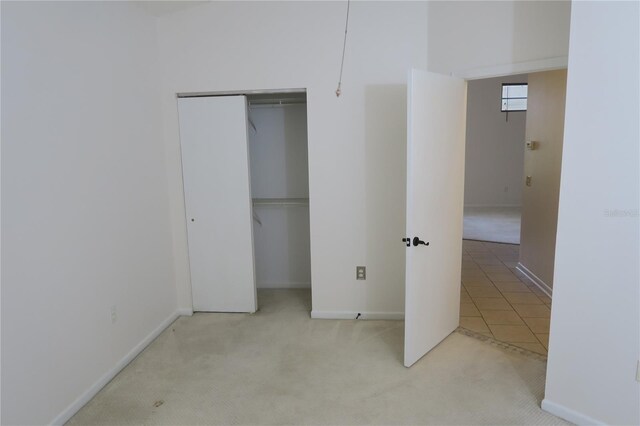 unfurnished bedroom with light colored carpet and a closet